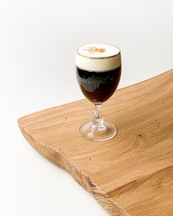 Irish coffee with a beautifull painted foam on wooden white background
