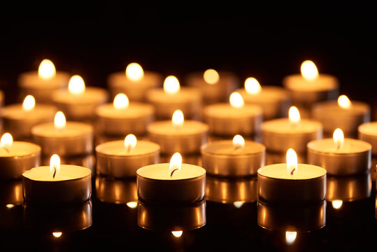selective focus of burning candles glowing in darkness
