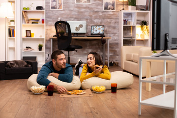 Couple sitting on the floor and watching TV in their living room