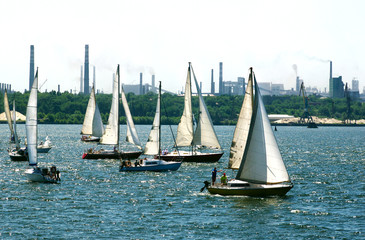 Fototapeta premium Sail boats on the background of the pipes metallurgical plant