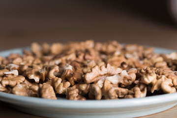 Many peeled walnuts on a blue plate close up still