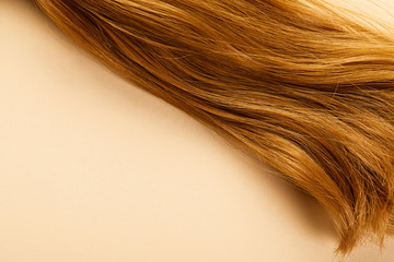 Naklejka premium Top view of brown hair on beige background