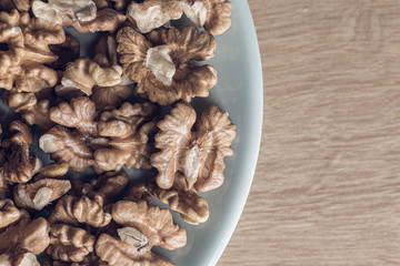 Many peeled walnuts on a blue plate close up still
