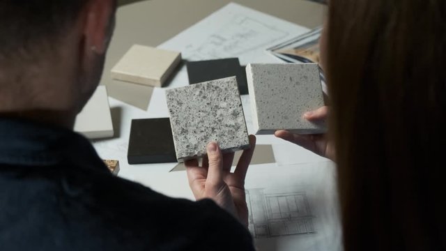 Man and woman choosing material samples close up. Team of architects discussing quartz materials for countertops in the kitchen. Artificial stone examples 4k