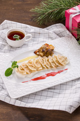 vareniki or dessert dumplings with apple and strawberry jam and cup of tea on wooden table