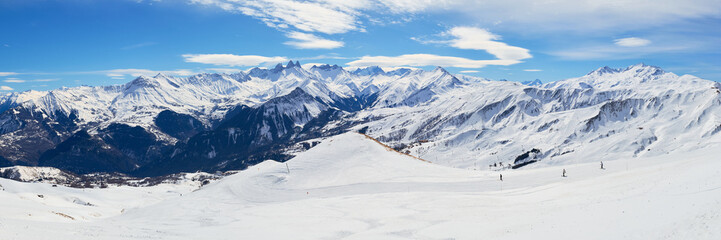 Les Sybelles ski domain in France. Panorama with slopes, skiers, and mountain peaks, on a sunny day...