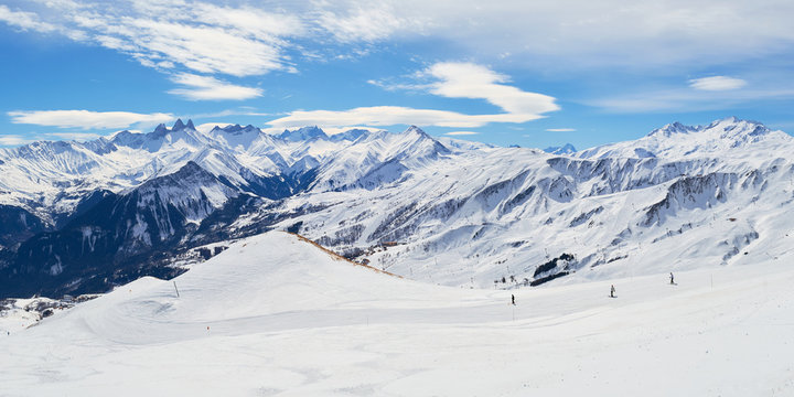 Les Sybelles ski slopes and surrounding white mountain peaks, on a sunny Winter day - panorama in the French alps.