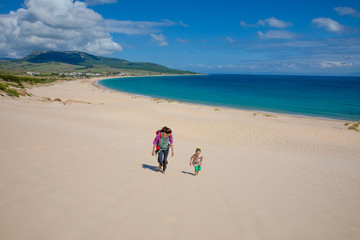landscape of wild natural beautiful Beach Bolonia in Tarifa, Cadiz, Andalusia, Spain, with woman and little girl walking. Copy or text space © Q