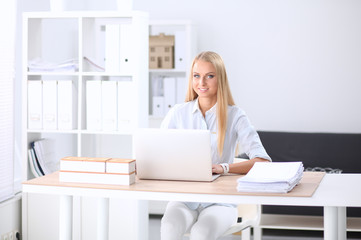Portrait of smiling receptionist using laptop computer and headset at office desk