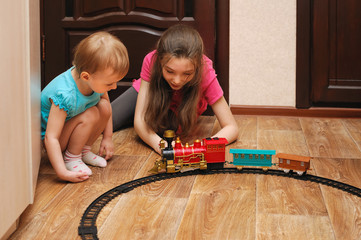 children sitting on the floor and playing in toy railway