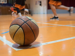 Basketball ball on court with free throw line, out of focus players in the background.