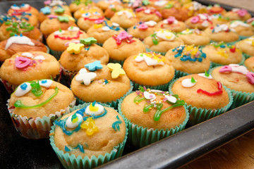 Close-up of a baking tray full of small homemade muffins with funny decoration ready for a children's birthday party