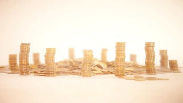 The concept of money. Columns of gold coins in the form of skyscrapers or Stonehenge. Close-up hands make up stacks of coins. Smoke. Garland.