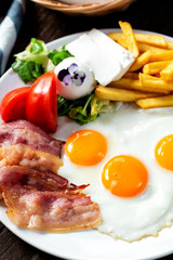 Close up of a tasty meal made from fried eggs and bacon along with side dishes