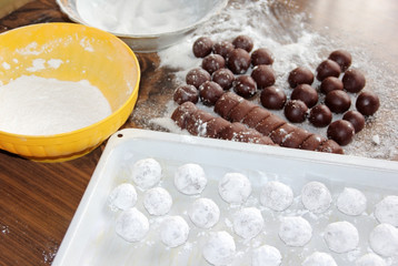A chocolate truffles being prepared on brown kitchen table.
