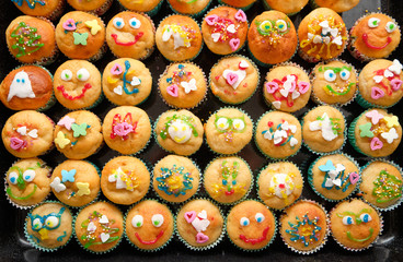 Close-up of a baking tray full of small homemade muffins with funny decoration ready for a children's birthday party