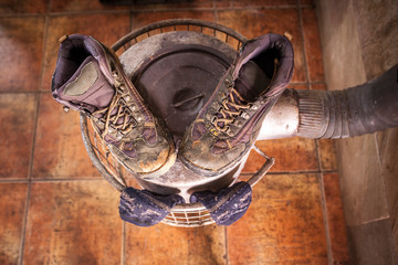 Wet used boots and socks drying over firewood stove