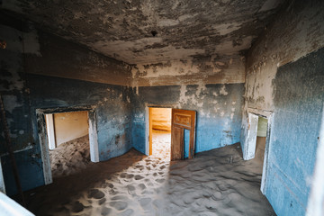Fototapeta na wymiar Sand Dune filling up abandoned Ghost Town House through doors and broken window