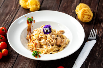 Yummy carbonara served on the plate and decorated with vegetables and a flower