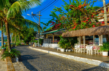 Fototapeta premium Seafront of Brigitte Bardot with palms and tables of restaurant in Buzios, Rio de Janeiro. Brazil. Cityscape of Buzios.