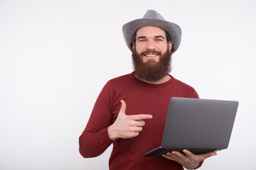 Portrait of happy young man pointing at his new laptop