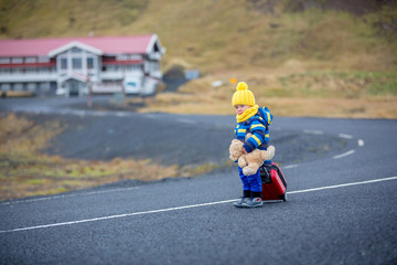 Obraz premium Cute toddler child, boy with teddy bear and suitcase in hand, running on a road in Iceland on a rainy day