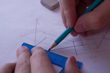 A man draws a diagram with a ruler, eraser and pencil. Design and create a project on a white sheet...