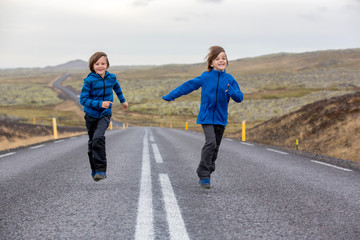 Fototapeta premium Kids running on an empty road in beautiful nature in Snaefellsjokull National Park in Iceland, autumntime