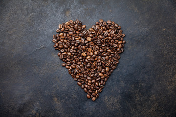 Coffee beans in shape of heart on dark rustic background