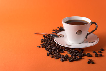 cup of aromatic coffee and coffee beans on an orange trendy background with space for text