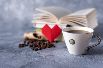  cup of coffee and coffee beans on a gray background and old books