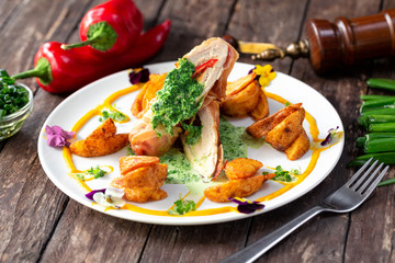 Chicken fillet with spinach and potatoes decorated with various vegetables along the plate