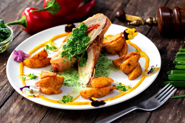 Chicken fillet with spinach and potatoes decorated with various vegetables along the plate