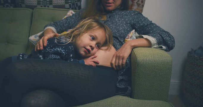 Toddler resting his head on pregnant mother's belly
