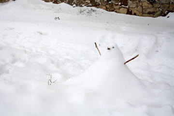 Small snowman in a snow covered garden. Selective focus.