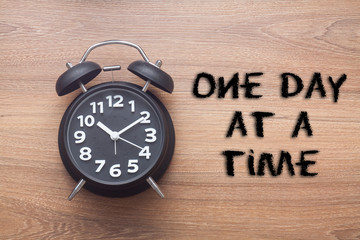 One day at a time -  inspirational advice handwriting with clock