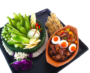 "Nam Prik Lon Lue" , Thai traditional cuisine menu, comprising of sweet porks , crispy fish and salty eggyolks with lot of vegetables set aside, served on black plate in white background
