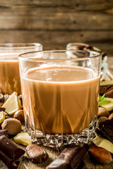 Sweet and strong alcohol drink. Chocolate liqueur with milk and dark chocolate pieces. Wooden background copy space