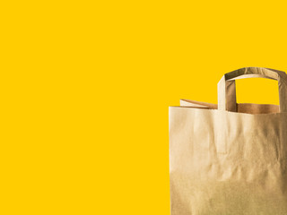 Brown kraft paper grocery shopping bag on yellow background. Plastic-free zero waste eco friendly...