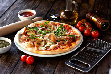 Pizza dish, rolling pin, grater, cherry tomatoes, pepper mill, oil and pizza sauce