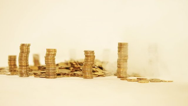The concept of money. Columns of gold coins in the form of skyscrapers or Stonehenge. Close-up hands make up stacks of coins. Smoke. Garland.