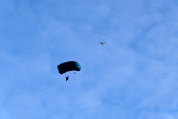 Skydiving. A dark parachute is in the blue sky.