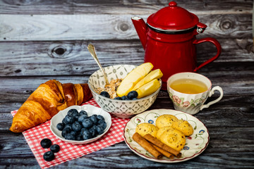 Petit déjeuner avec thé citron biscuits cannelle myrtilles fraiches et muesli pommes