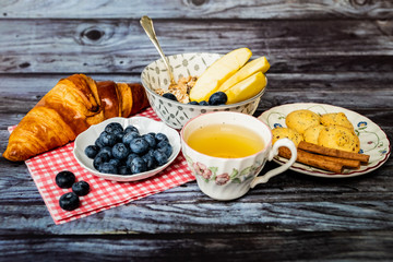 Petit déjeuner sain thé avec croissant biscuits cannelle muesli pommes et myrtilles