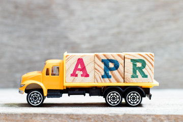 Truck hold letter block in word apr on wood background (Concept for month April)