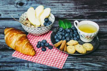 Petit déjeuner sain thé avec croissant biscuits cannelle muesli pommes et myrtilles