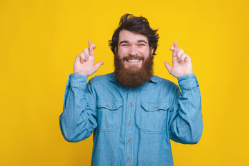 Happy man with beard crossing fingers for luck