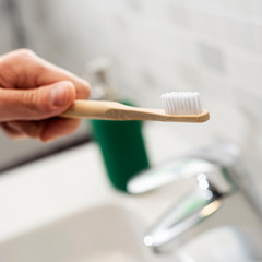 Fototapeta na wymiar man using a bamboo toothbrush in the bathroom