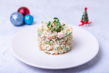 Olivier salad on a white plate, decorated with pea sprouts. Traditional New Year and Christmas Russian salad. Close-up, selective focus, white background.