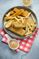 Grey plate with breaded fish fillet and french fries, vertical shot, selective focus